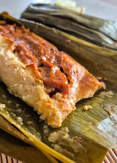 Masa-Teig wird auf Bananenblätter gestrichen, bevor die Füllung hinzukommt.