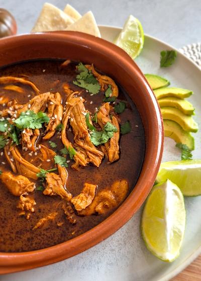 Traditionelles Gericht aus Mexico - Mole Poblano - mit Limetten, Tortilla und Avocado.