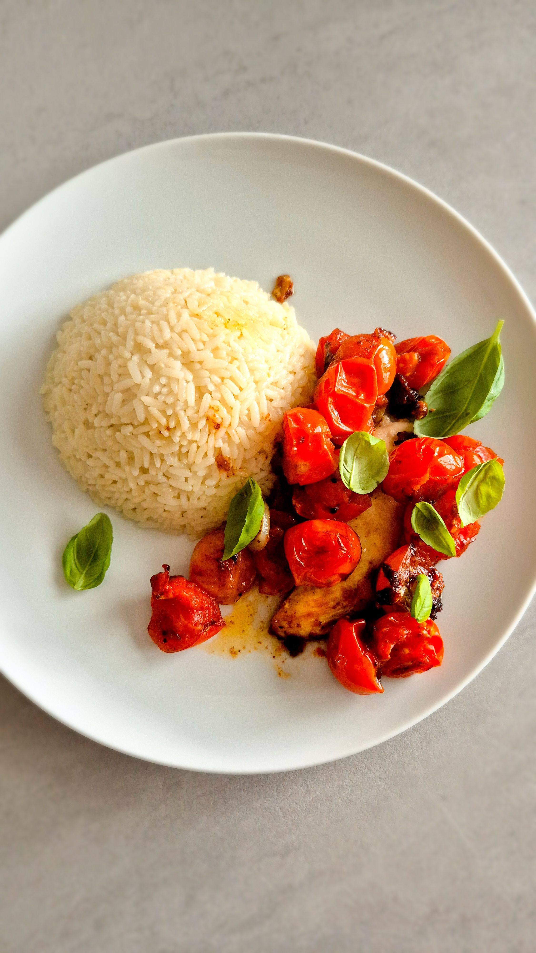 Hähnchen Caprese mit Reis und Basilikum auf einem Teller.