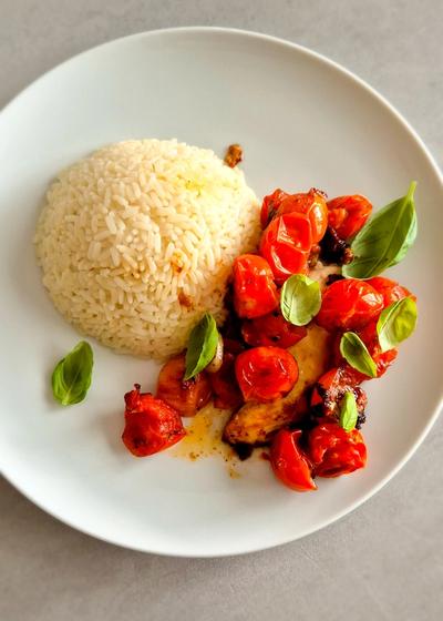 Hähnchen Caprese mit Reis und Basilikum auf einem Teller.