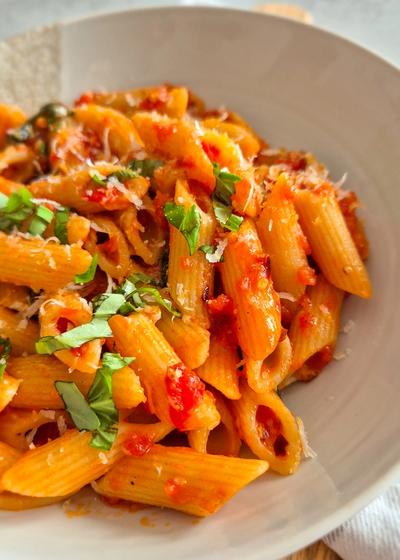 Penne all'Arrabbiata mit scharfer Chili und Perocino auf einem Teller serviert.