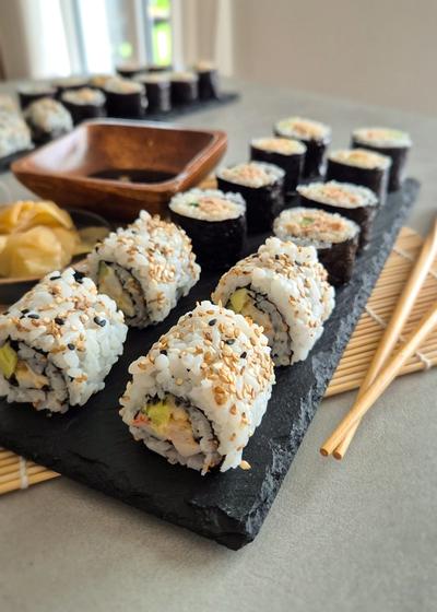 California Inside Out Rolls (Uramaki) mit einer leicht scharfen Mischung aus Surimi, Garnelen, Gurke und Avocado.