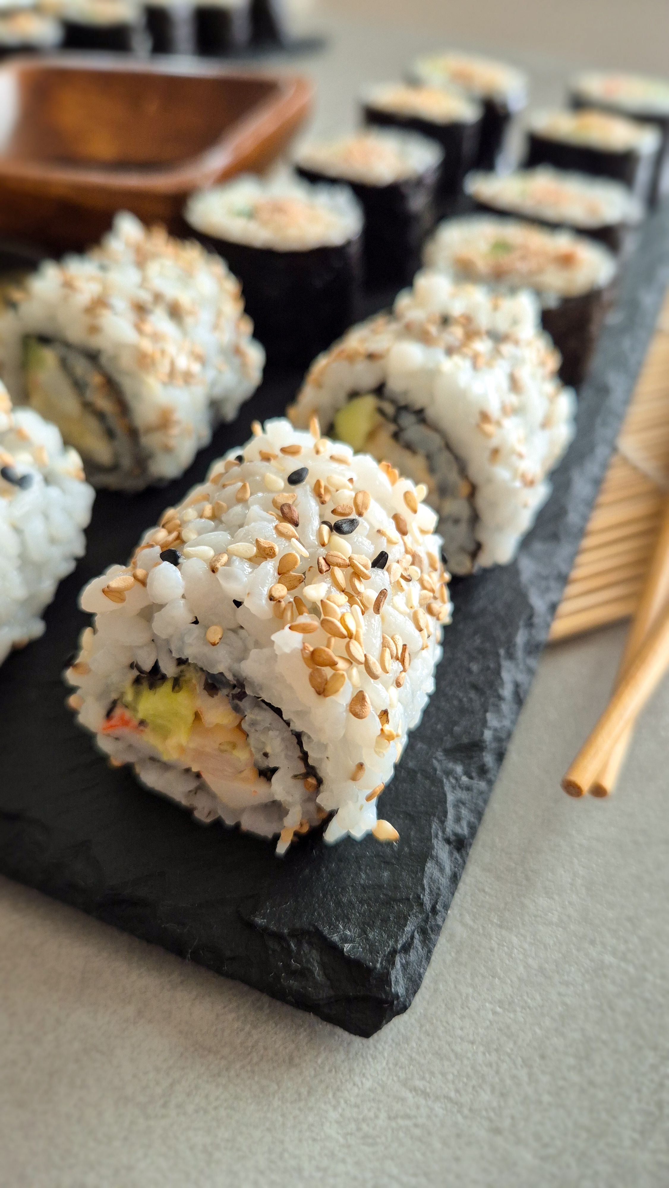 California Inside Out Rolls (Uramaki) mit einer leicht scharfen Mischung aus Surimi, Garnelen, Gurke und Avocado. 