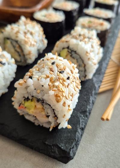 California Inside Out Rolls (Uramaki) mit einer leicht scharfen Mischung aus Surimi, Garnelen, Gurke und Avocado.
