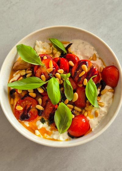Cremiger Burrata Dip mit gerösteten Honig-Tomaten und Pinienkernen in einer Schale.