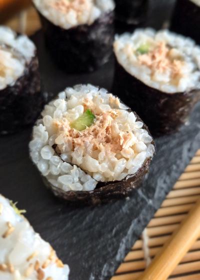 Maki mit Gurke und einer mild-scharfen Tunfisch-Füllung auf einer Platte serviert.