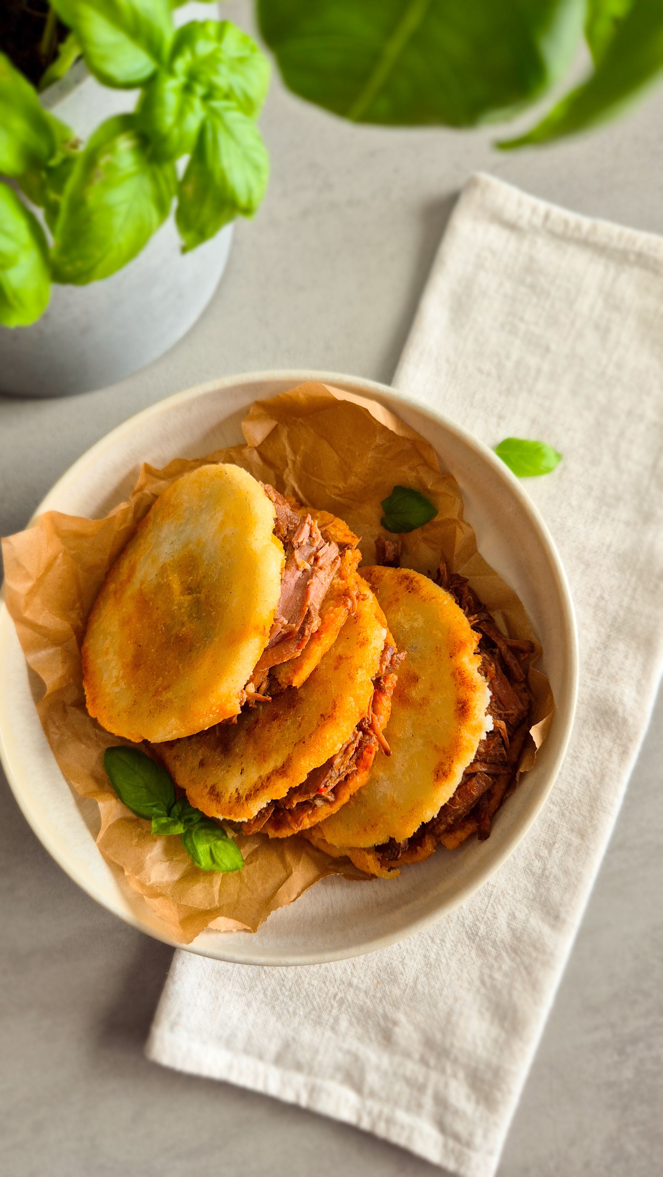 Venezolanische Arepas aus P.A.N. Maismehl mit Carne Mechada auf einem Teller.