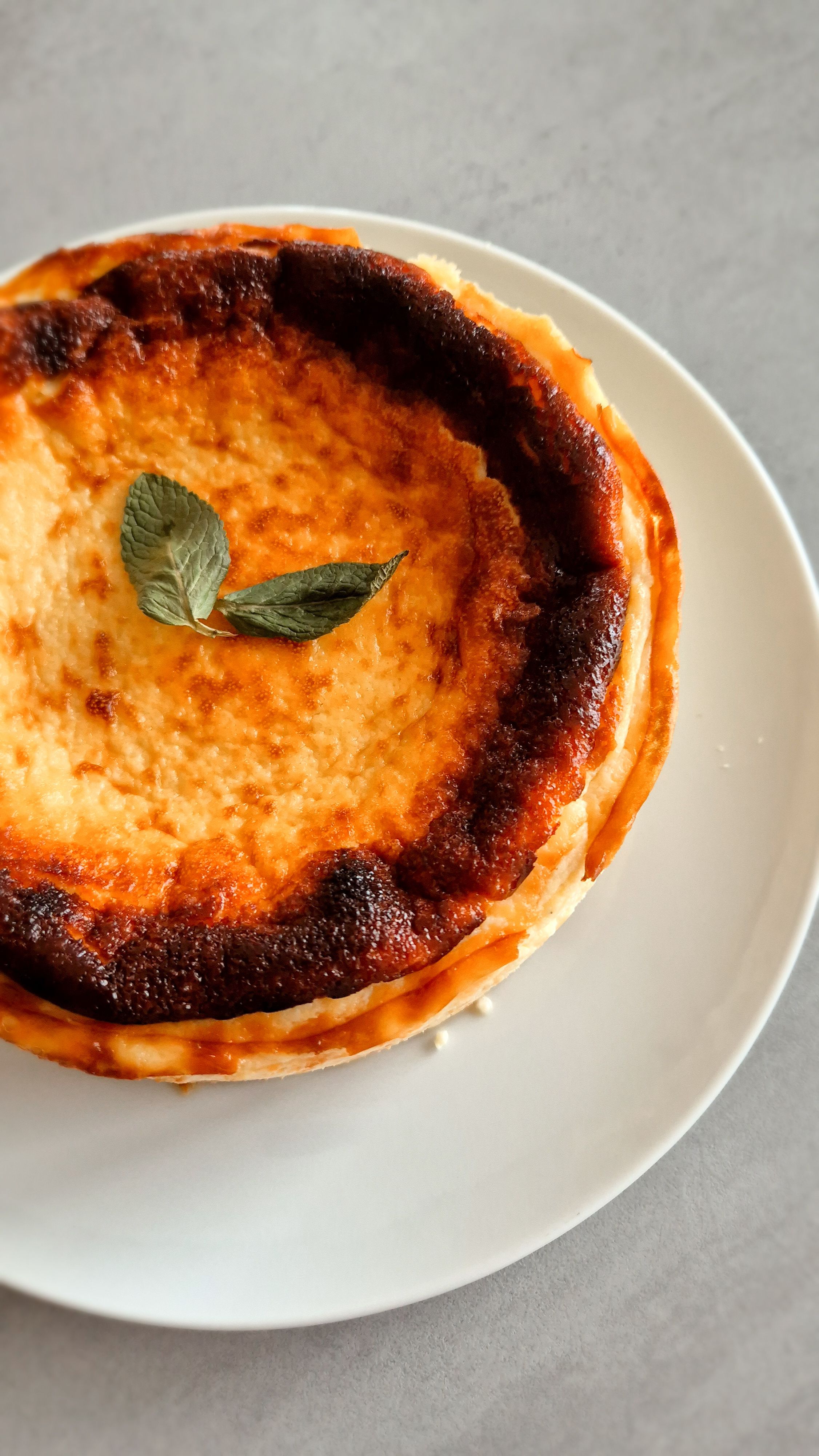 Cremiger San Sebastian Cheesecake mit einer dunkelbraun karamellisierten Kruste auf einem Teller.