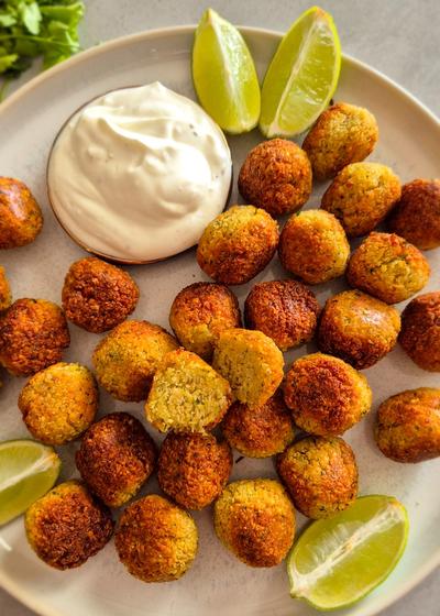Ein rustikaler Teller mit knusprigen Falafel mit Limetten-Wedges.