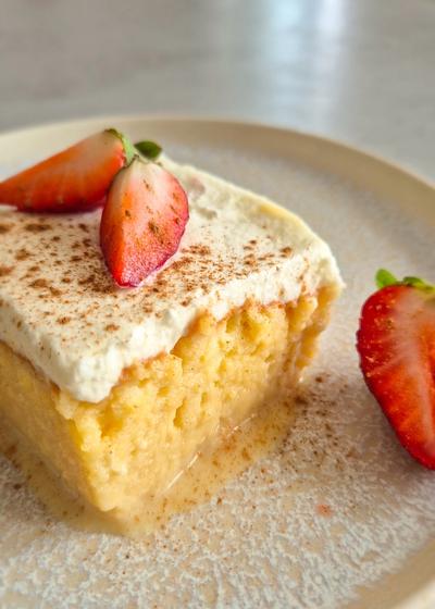 3-Milch-Kuchen (Tres Leches Cake) mit frischen Erdbeeren auf einem Teller serviert.