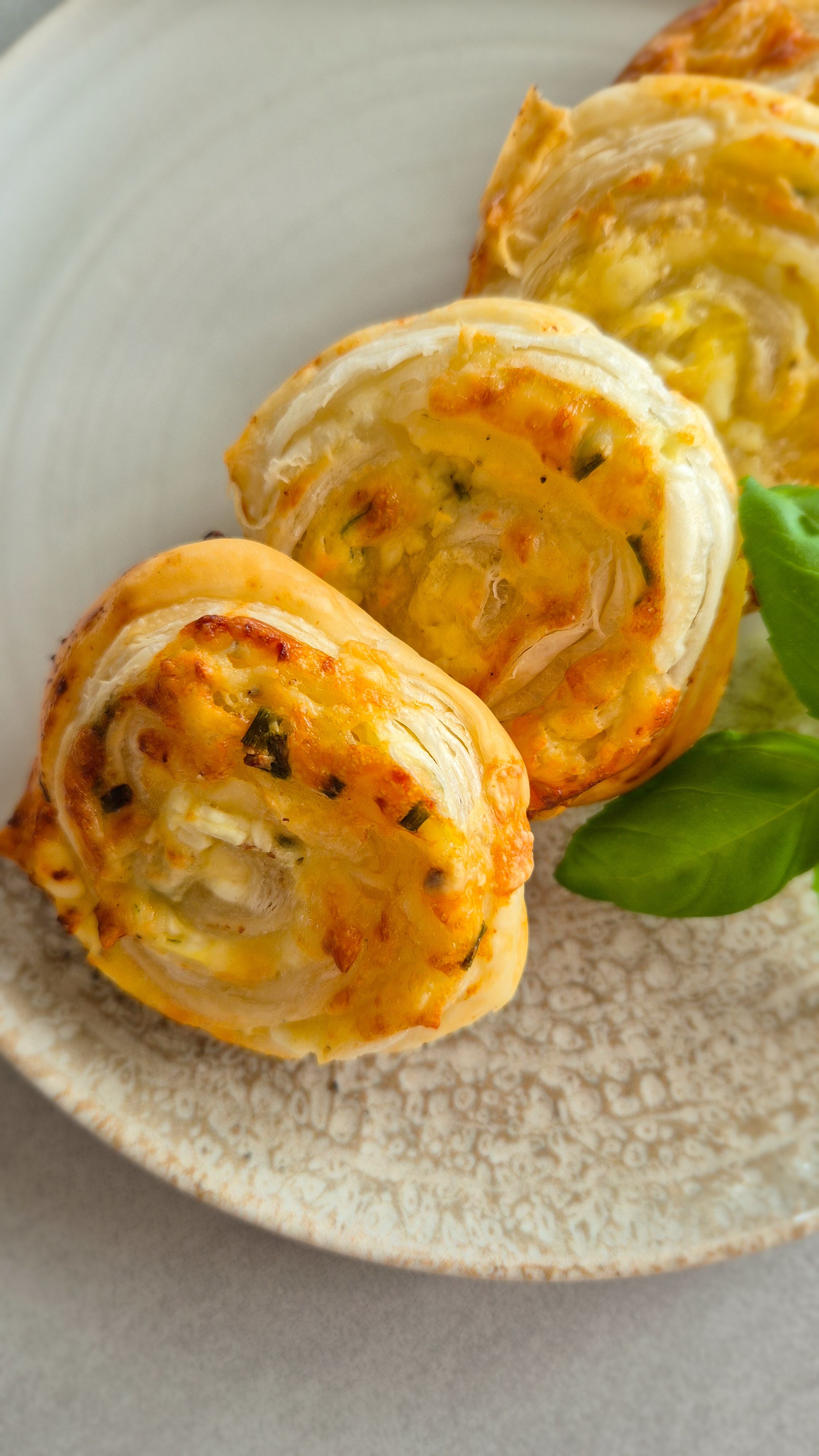 Knusprige, vegetarische Blätterteigschnecken mit Hüttenkäse-Füllung auf einem Teller.