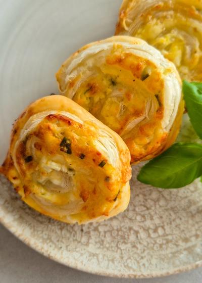 Knusprige, vegetarische Blätterteigschnecken mit Hüttenkäse-Füllung auf einem Teller.