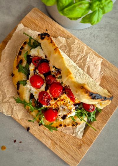 Ein Pizzasandwich mit Pesto Rosso, Burrata und Rucola auf einem Teller.