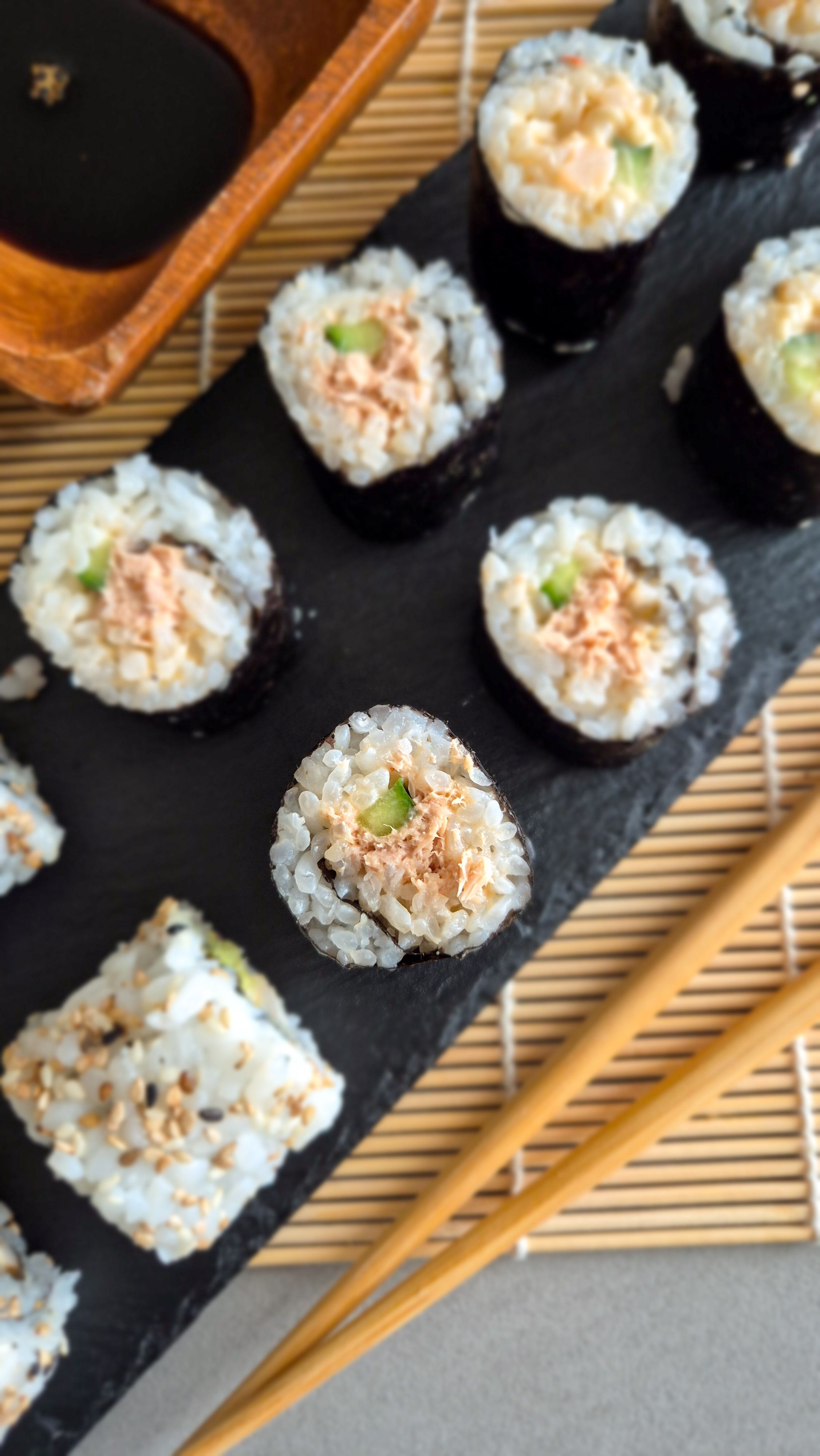 Spircy Tuna Maki Rolls auf einer Schieferplatte zu Sojasauce und Wasabi serviert.