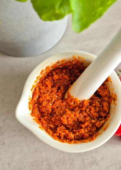 Rotes Pesto - Pesto Rosso - aus getrockneten Tomaten, Mandeln und Pinienkernen in einem Mörser.