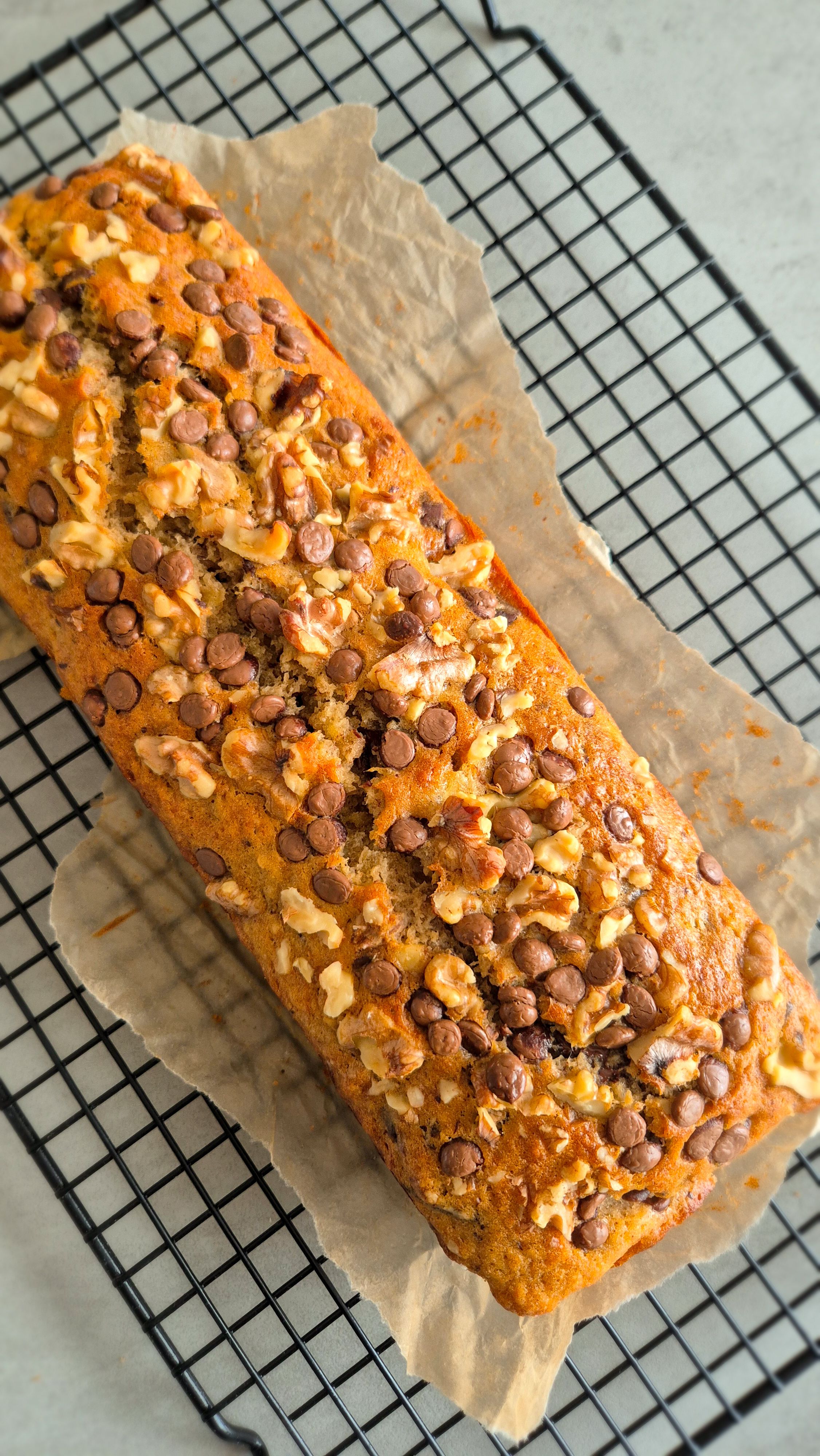 Frisch gebackenes Bananenbrot mit Walnüssen und Schokoladen-Chunks auf einem Rost.