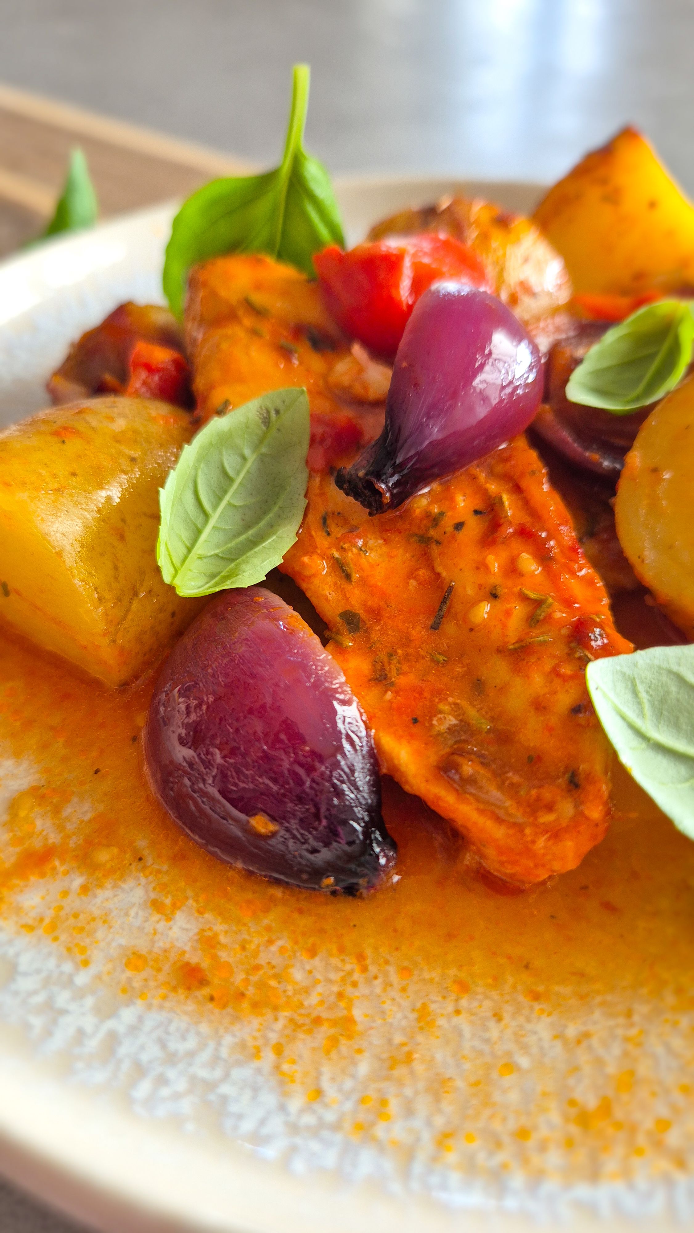 Einfaches Blechgericht mit Hähnchenbrust, Kartoffeln und Tomaten auf einem Teller serviert.