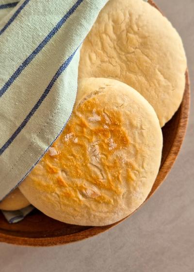 Fluffiges Pita-Brot in einer Holzschale mit einem Tuch umwickelt.