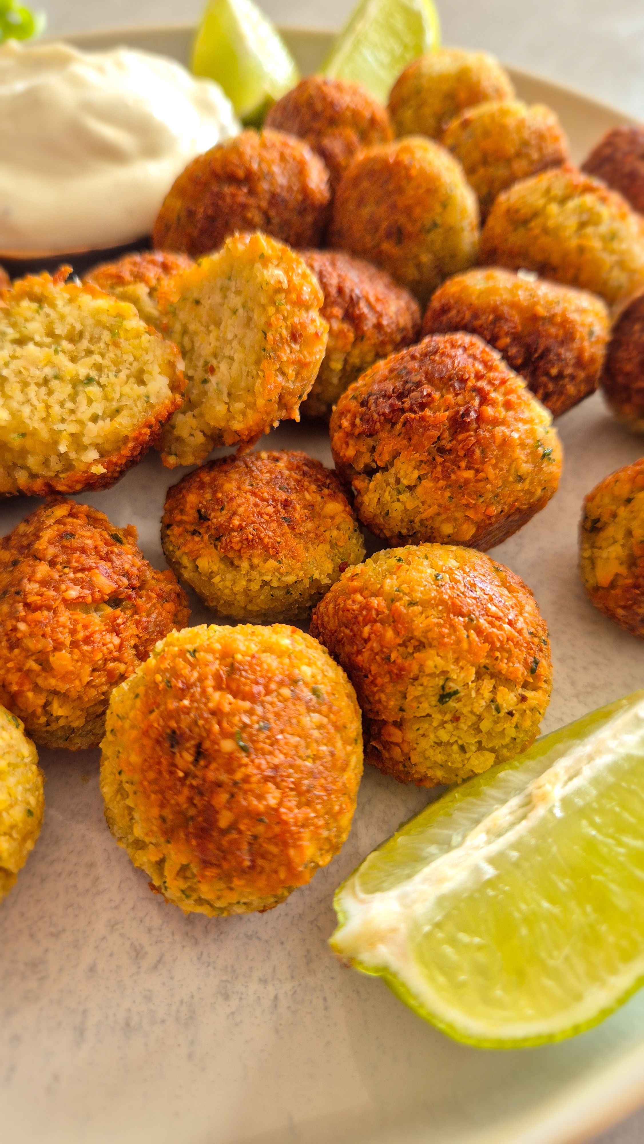 Ein rustikaler Teller mit knusprigen Falafel mit Limetten-Scheiben und Tzatziki.