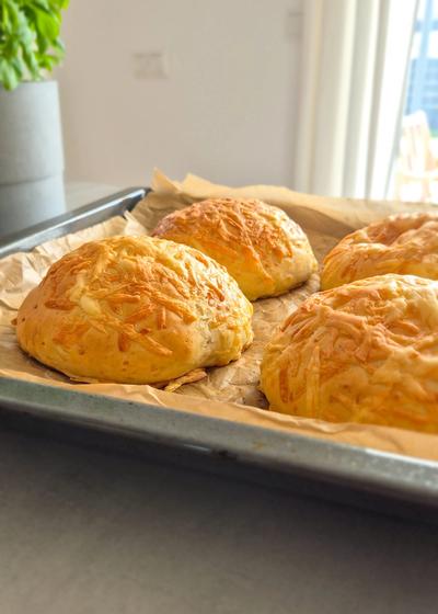 Selbstgebackene weiche Käsebrötchen frisch aus dem Ofen auf einem Blech.