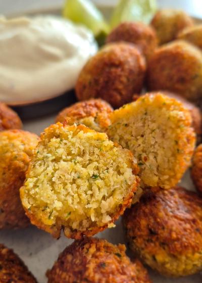 Knusprige Falafel, aufgeschnitten, zu einem Knoblauch-Dip und Limetten. Passend für eine Pita-Füllung.