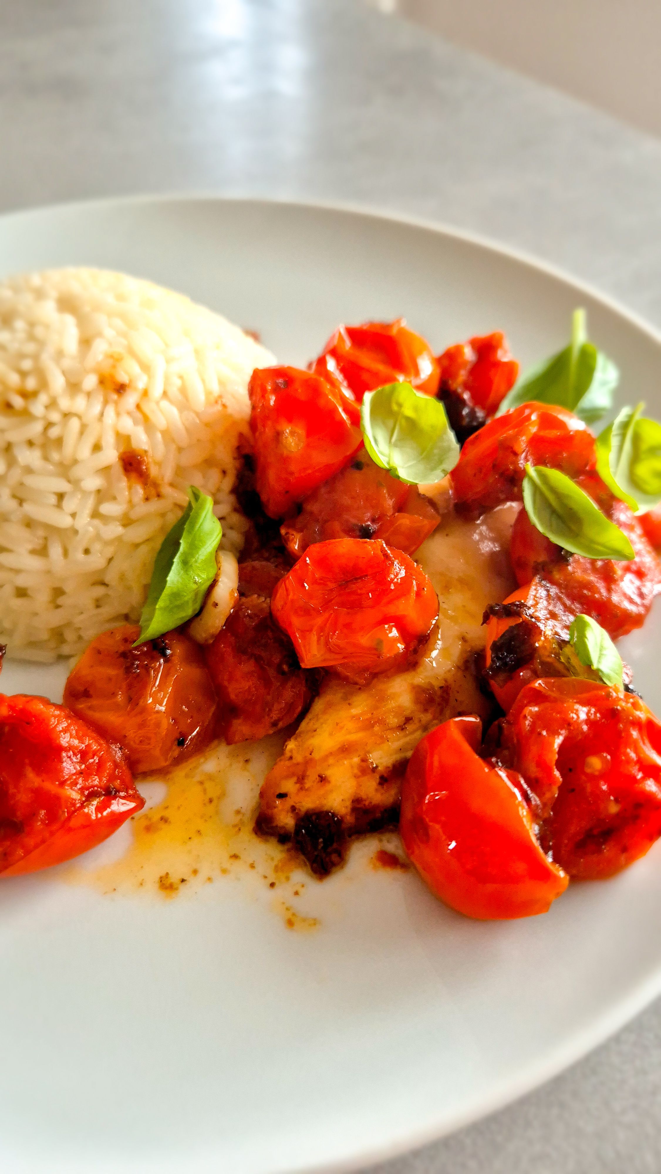 Hähnchen Caprese mit Reis und Basilikum auf einem Teller.