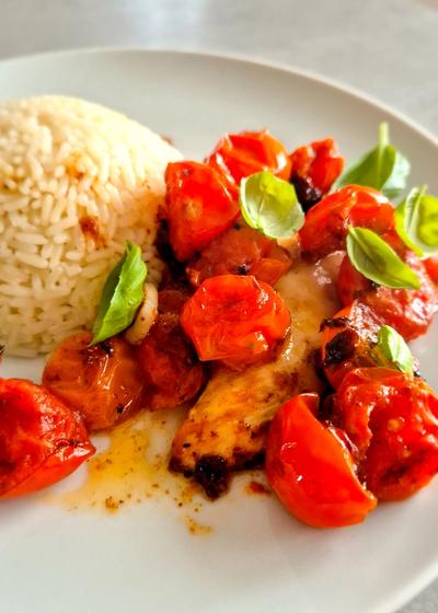 Hähnchen Caprese mit Reis und Basilikum auf einem Teller.