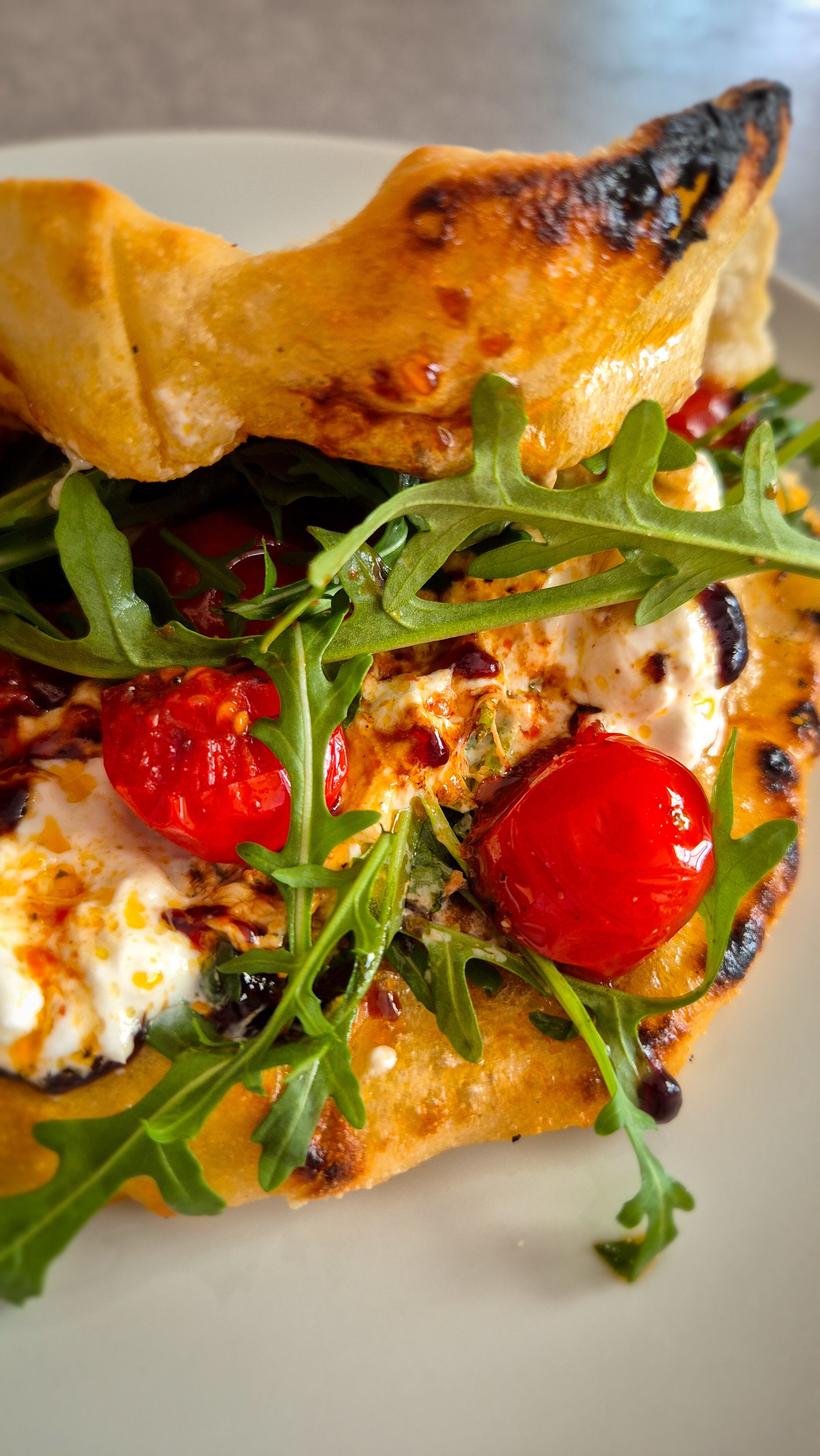 Ein Pizzasandwich mit Pesto Rosso, Burrata und Rucola auf einem Teller.