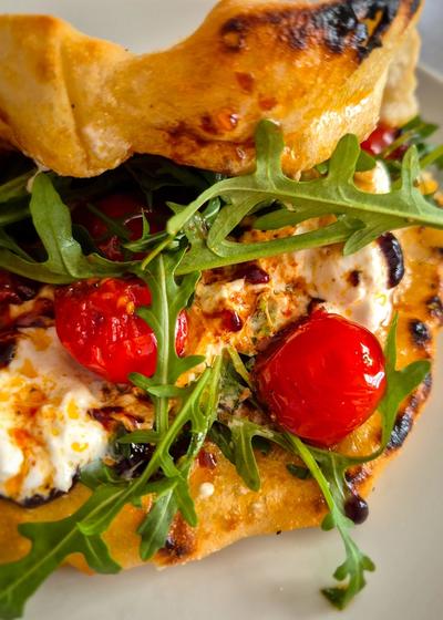 Ein Pizzasandwich mit Pesto Rosso, Burrata und Rucola auf einem Teller.