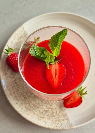 Ein Dessert-Glas cremige Panna Cotta mit frischer Erdbeersauce, Erdbeeren und Minze.
