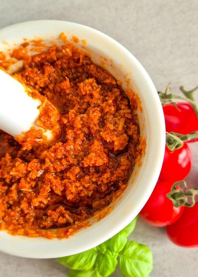 Rotes Pesto - Pesto Rosso - aus getrockneten Tomaten, Mandeln und Pinienkernen in einem Mörser.