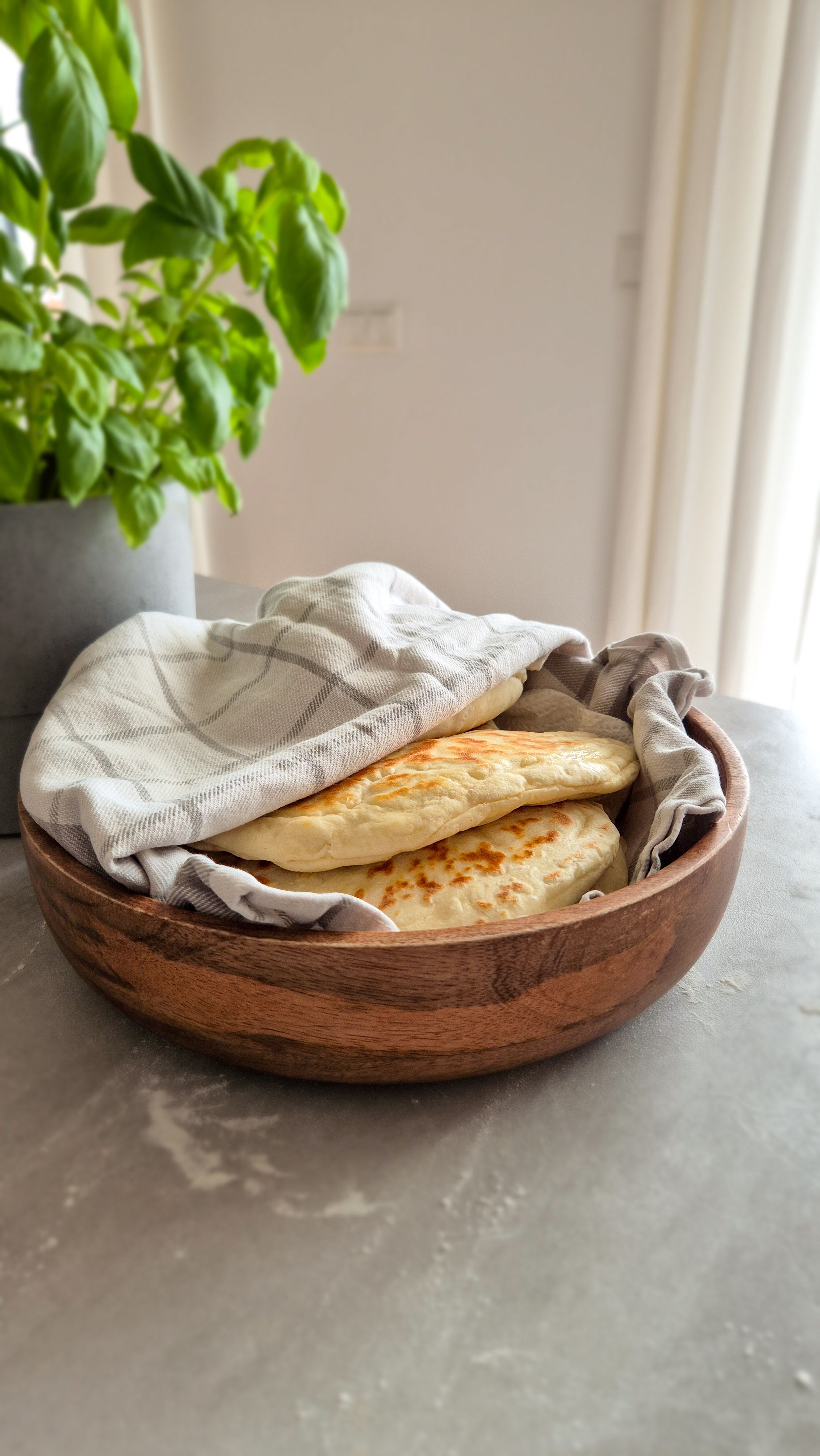 Teigtaschen mit einer Kartoffel-Käse-Füllung in einem Tuch gewickelt in einer Holzschale serviert.