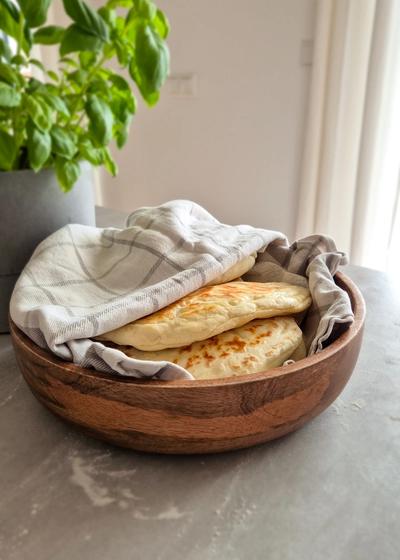 Teigtaschen mit einer Kartoffel-Käse-Füllung in einem Tuch gewickelt in einer Holzschale serviert.