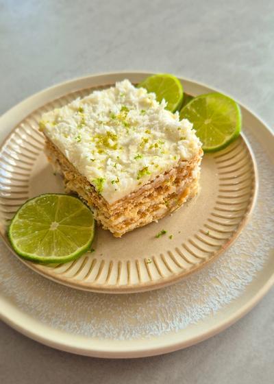 Ein Stück Carlota de Limón (mexikanischer Limettenkuchen) auf einem beigen Teller mit Limettenscheiben serviert.