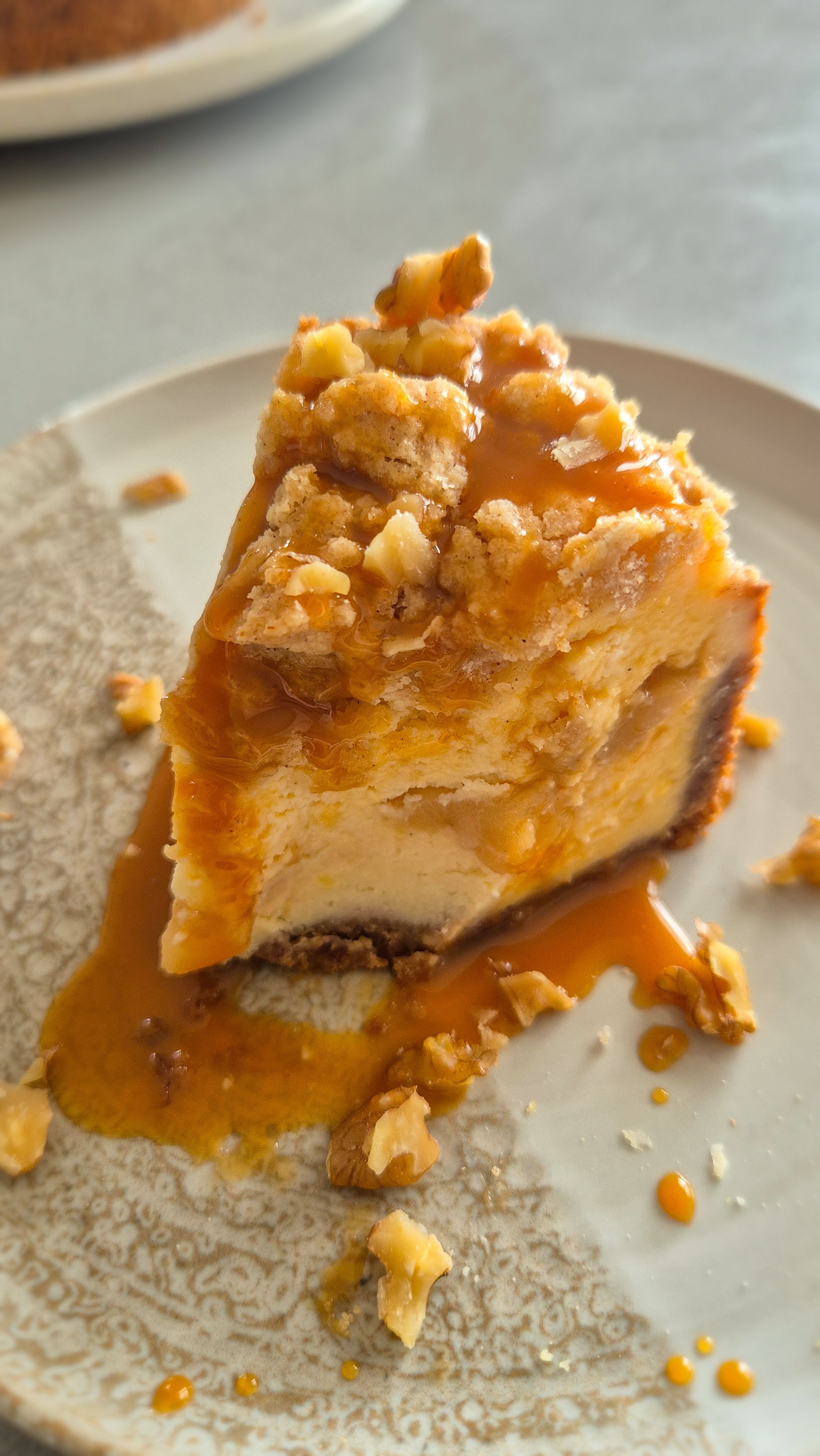 Ein Stück cremiger Cheesecake mit fruchtig, weicher Apfel-Zimt-Schicht und Knusper-Streuseln auf einem Teller serviert.