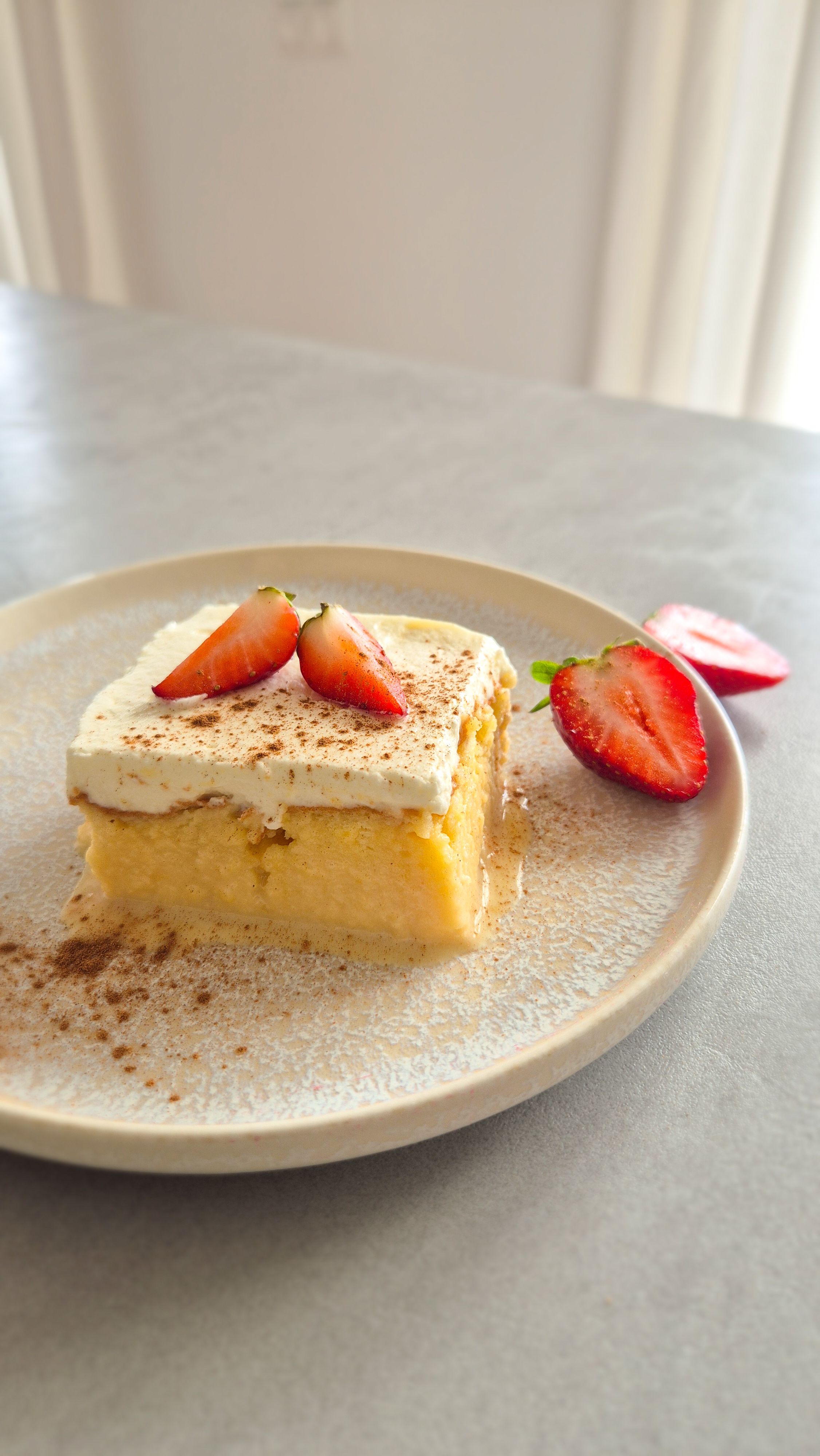 Saftiger, in Milch getränkter Kuchen aus Lateinamerika (Tres Leches) mit Sahnehaube und Erdbeeren serviert.