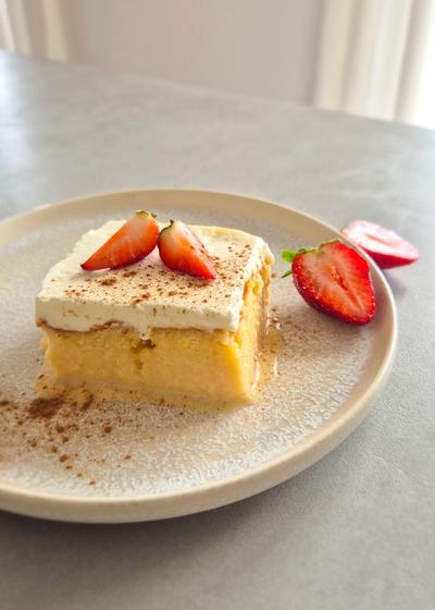 Saftiger, in Milch getränkter Kuchen aus Lateinamerika (Tres Leches) mit Sahnehaube und Erdbeeren serviert.