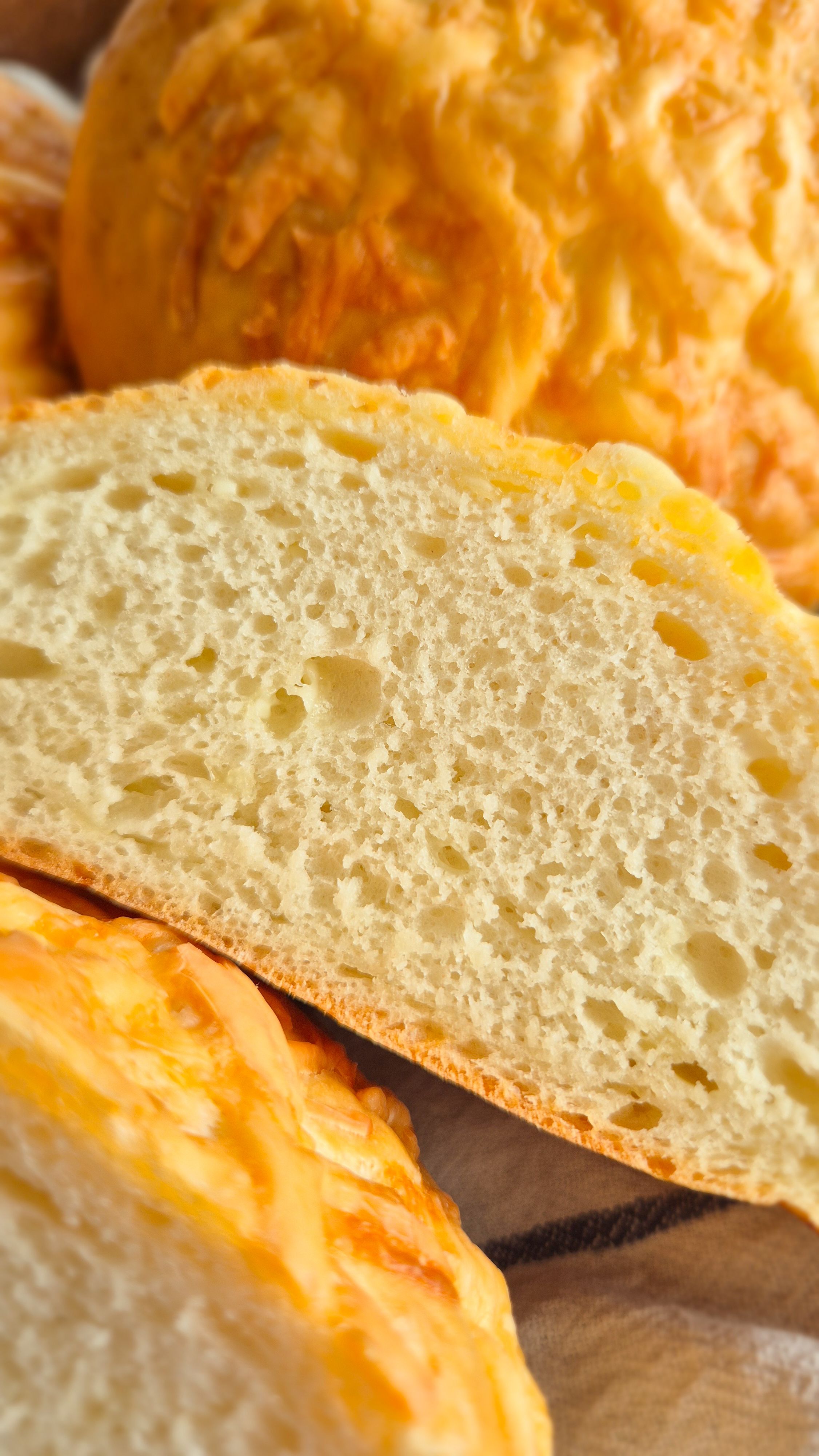 Querschnitt eines fluffigen selbstgebackenen Käsebrötchens.