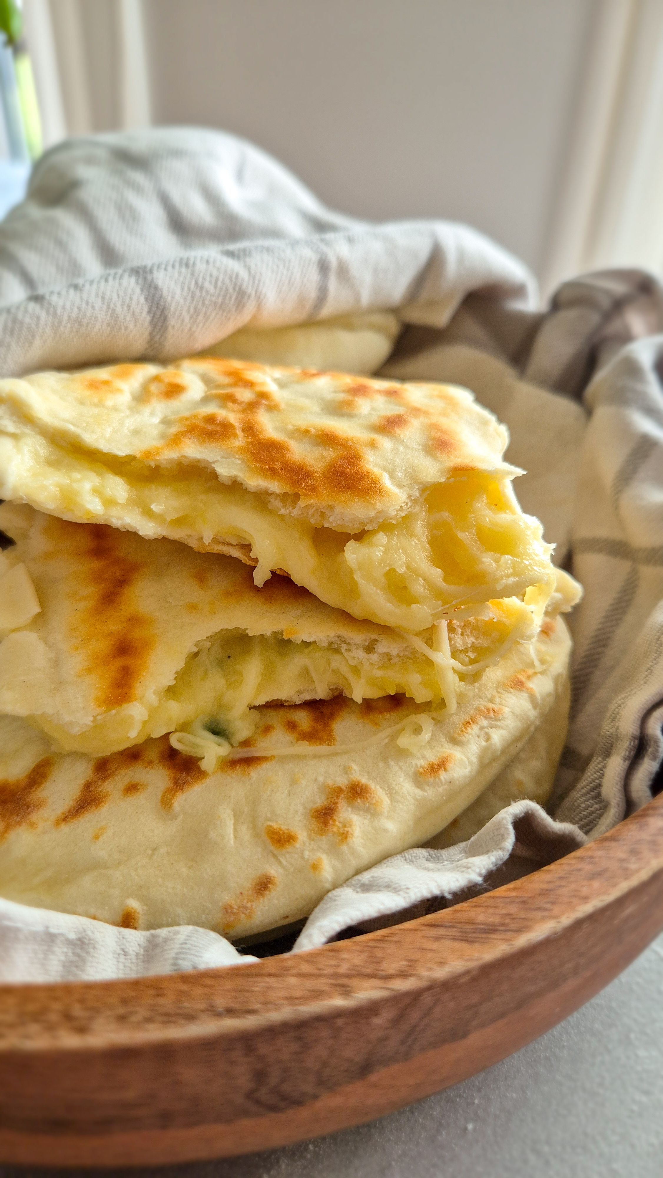 Teigtaschen mit einer Kartoffel-Käse-Füllung in einem Tuch gewickelt in einer Holzschale serviert.