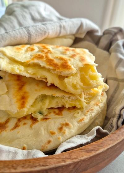 Teigtaschen mit einer Kartoffel-Käse-Füllung in einem Tuch gewickelt in einer Holzschale serviert.