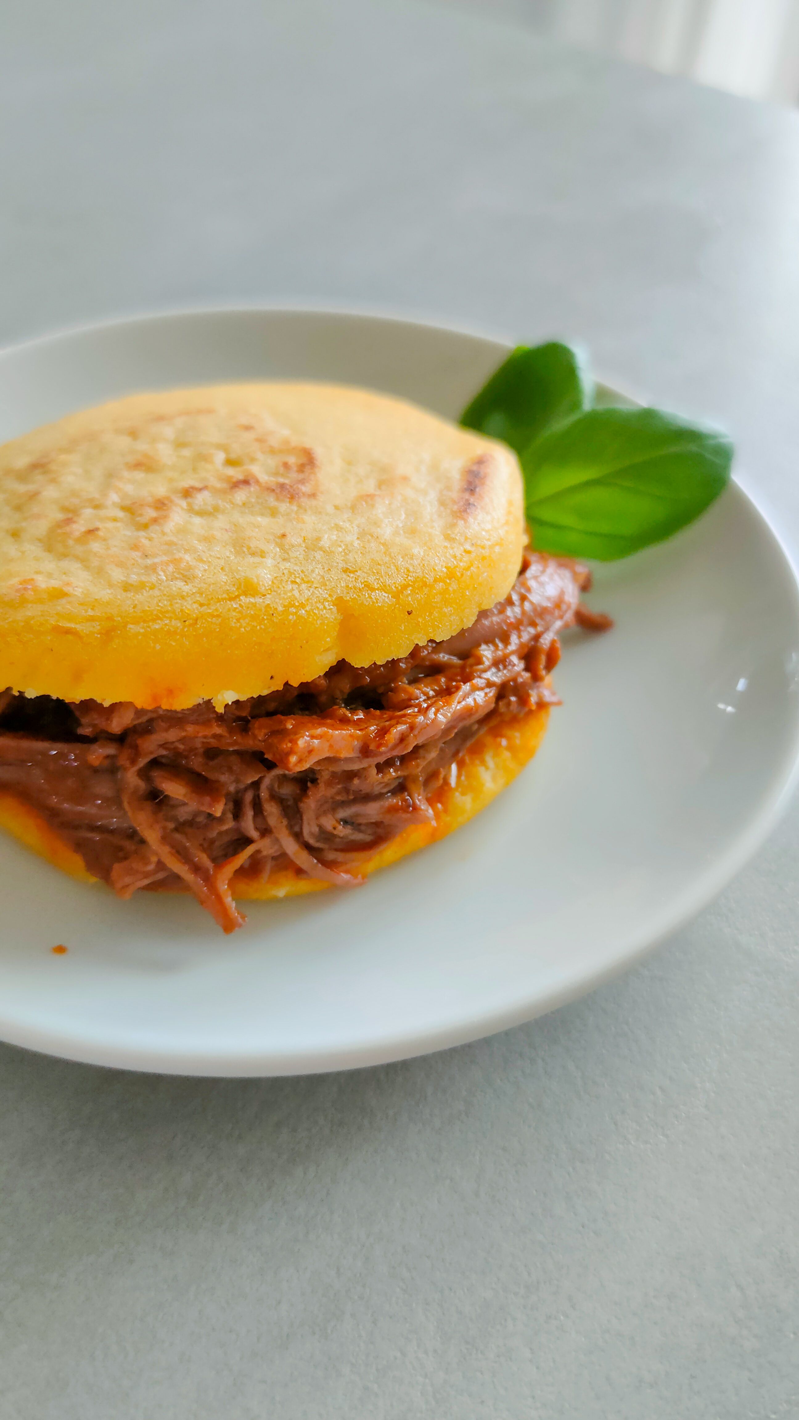 Venezolanische Arepas aus P.A.N. Maismehl mit Carne Mechada auf einem Teller.
