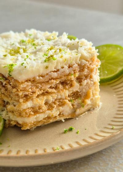 Ein Stück Carlota de Limón (mexikanischer Limettenkuchen) auf einem beigen Teller mit Limettenscheiben serviert.