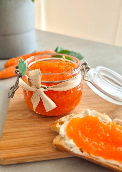 Ein dekorativ angerichtetes Glas Hasenfrühstück (Karotten-Apfel-Marmelade) mit einem Baguette zum Frühstück.