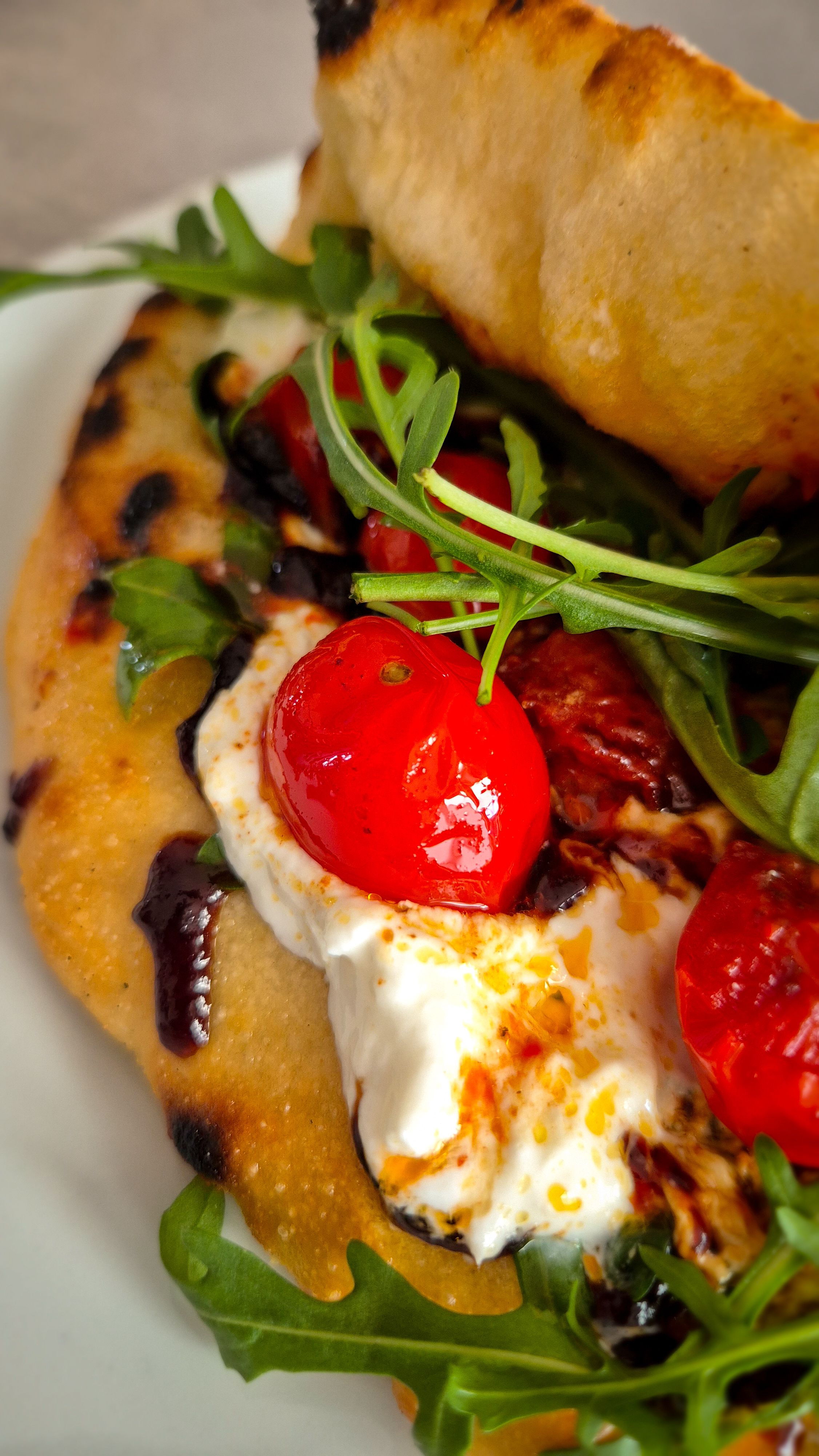 Pesto Rosso auf einem Pizza Sandwich mit Burrata, Rucola und Tomaten, Caprese.