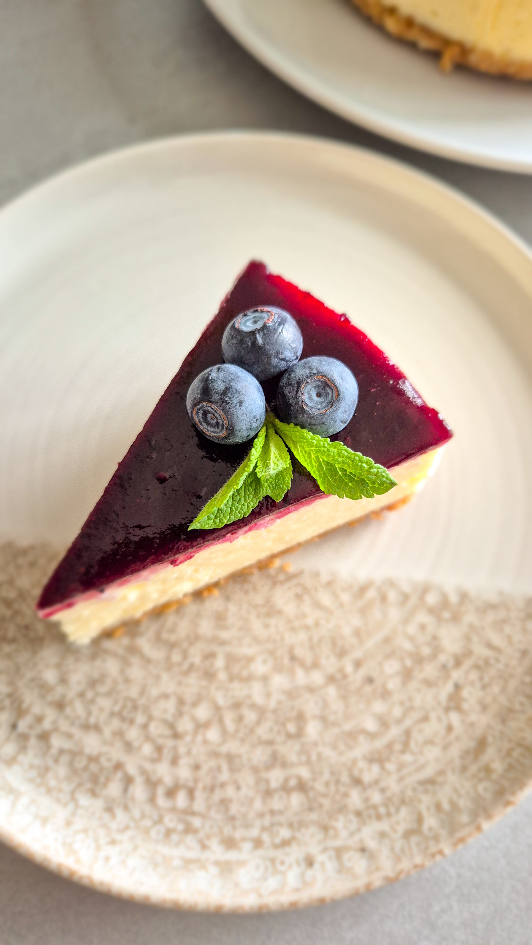 Cremiger New York Cheesecake mit glattem Heidelbeerspiegel und nussigem Mandelboden