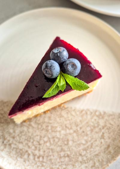 Cremiger New York Cheesecake mit glattem Heidelbeerspiegel und nussigem Mandelboden