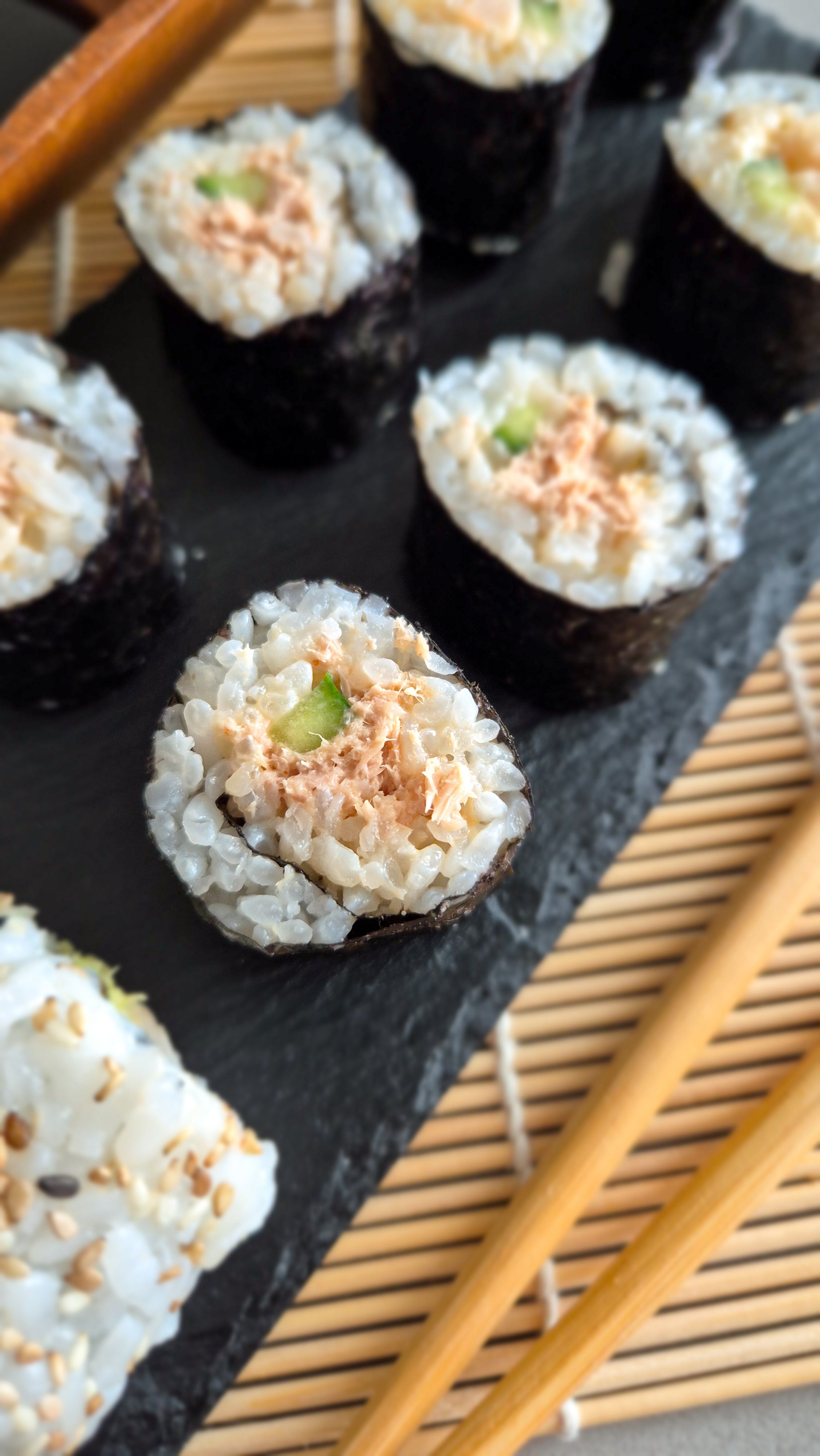 Maki mit Gurke und einer mild-scharfen Tunfisch-Füllung auf einer Platte serviert.