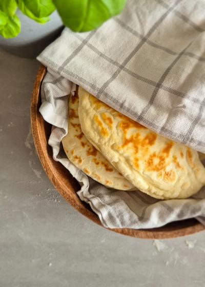 Teigtaschen mit einer Kartoffel-Käse-Füllung in einem Tuch gewickelt in einer Holzschale serviert.