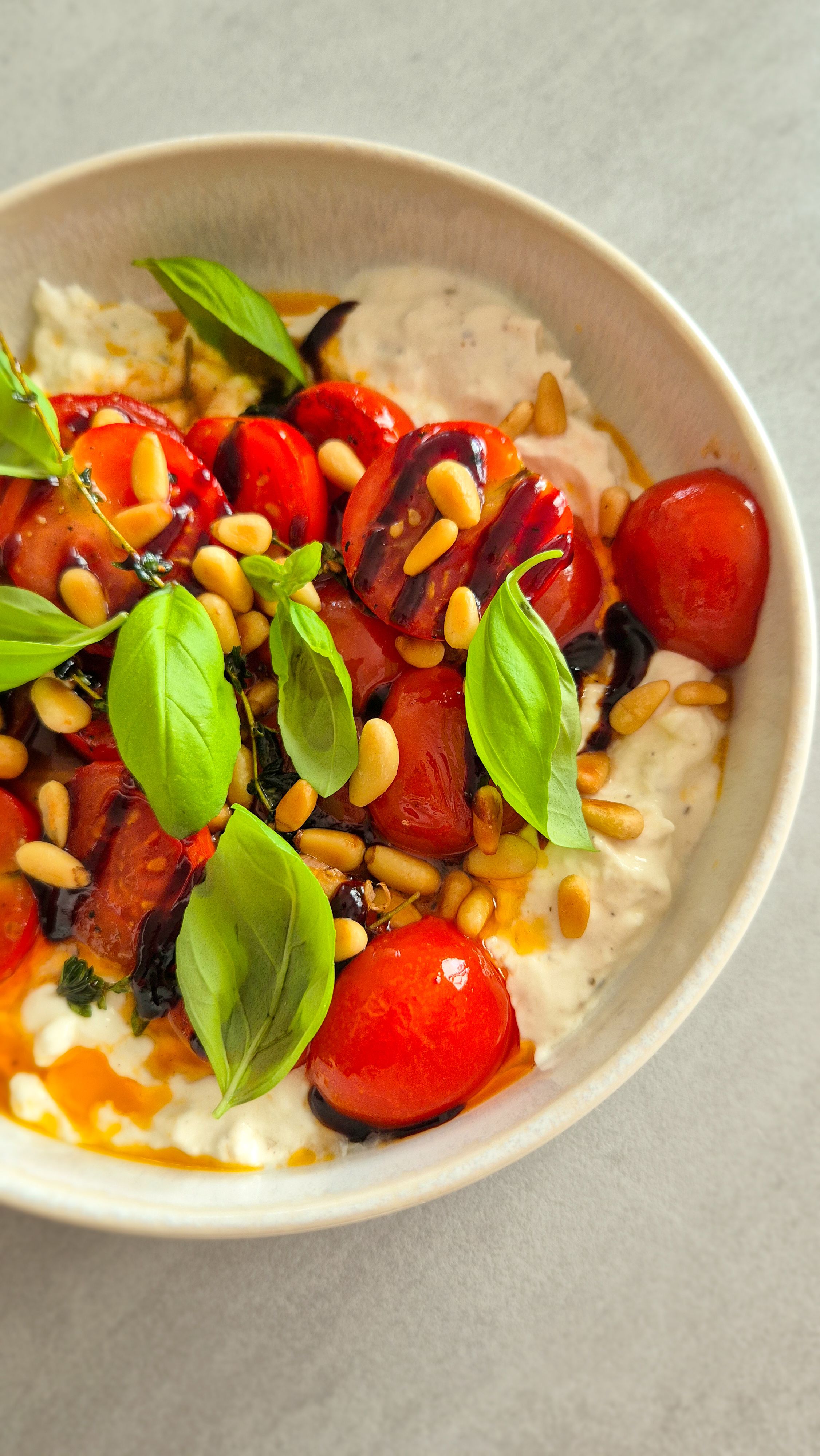 Cremiger Burrata Dip mit gerösteten Honig-Tomaten und Pinienkernen in einer Schale.