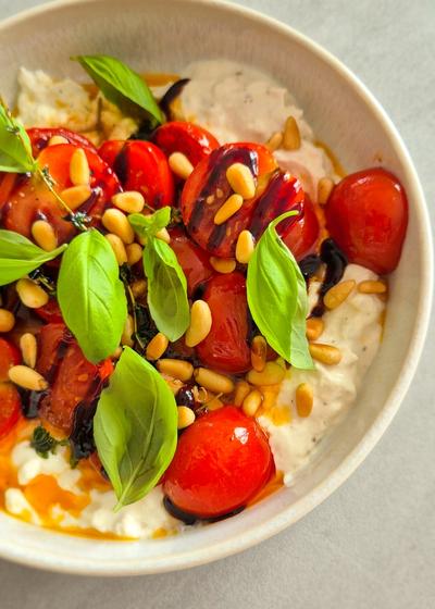 Cremiger Burrata Dip mit gerösteten Honig-Tomaten und Pinienkernen in einer Schale.